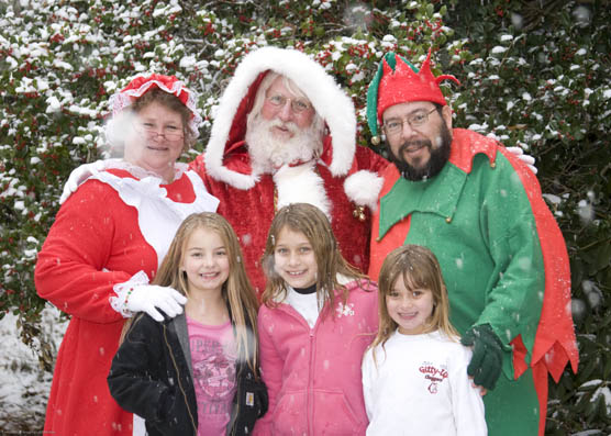 Santa, Mrs. Claus and Freddy the Elf pose with some children